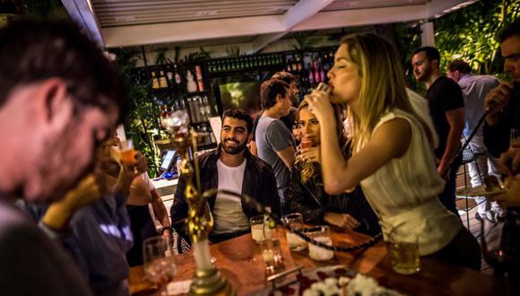 Alexandra Lovera (de pie) toma un shot en el restaurante La Esquina, popular entre la alta sociedad de Chacao. (Bloomberg)