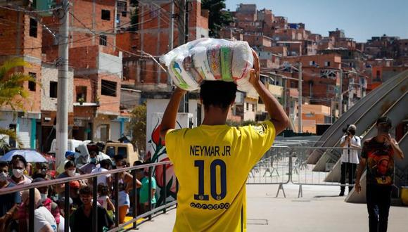 Varias personas reciben donaciones de comida el 23 de marzo de 2021, en la favela de Paraisopolis, en la avenida Paulista, en Sao Paulo, Brasil, en medio de la pandemia de coronavirus. (Foto: EFE/ Fernando Bizerra).