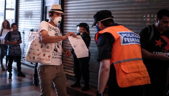 Coronavirus en Argentina: Un hombre le muestra a la policía un certificado para poder circular libremente en la Estación Ferroviaria de Constitución, Buenos Aires. (Foto: EFE/ Juan Ignacio Roncoroni).