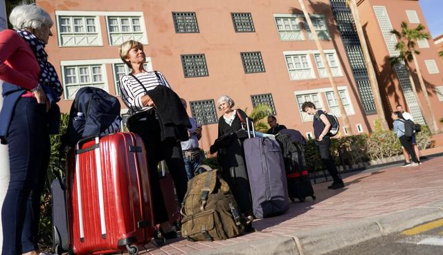 Los turistas llevan sus pertenencias cuando salen del hotel H10 Costa Adeje Palace, después de que se levantó su cuarentena. (Reuters).