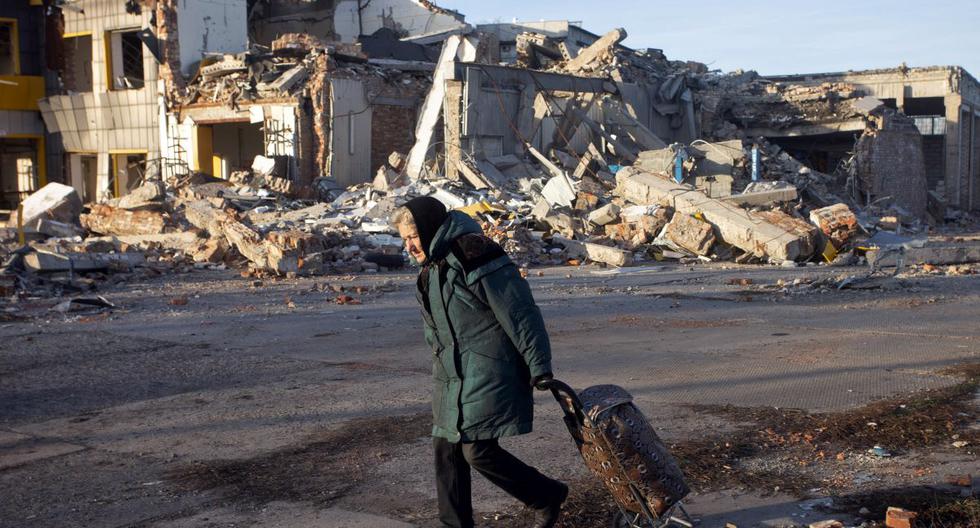 Una anciana tira de una maleta junto a un edificio destruido en Bakhmut, región de Donetsk, el 4 de diciembre de 2022, en medio de la invasión rusa de Ucrania. (Yevhen TITOV / AFP).