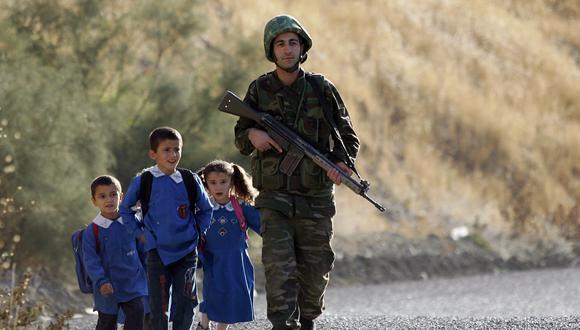 Imagen referencial | Un soldado turco, flanqueado por niños camino a la escuela, patrulla en una carretera en la provincia de Sirnak. (Foto de MUSTAFA OZER / AFP)