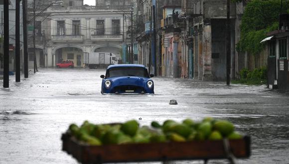 Un viejo automóvil estadounidense circula por una calle inundada en La Habana. (Foto de Yamil LAGE / AFP)
