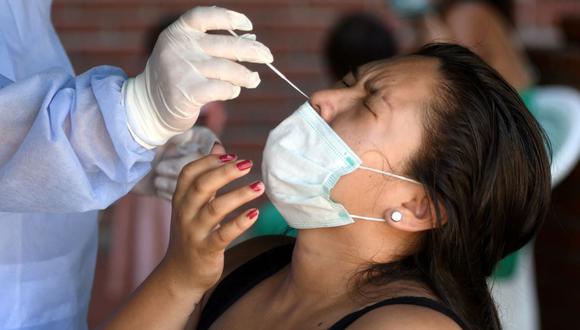 Un trabajador de la salud toma muestras de una mujer en un centro de pruebas de coronavirus COVID-19 en Santa Cruz, Bolivia, el 29 de diciembre de 2021. (RODRIGO URZAGASTI / AFP).