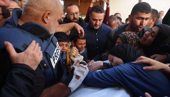 La esposa (R) de Hamza Wael Dahdouh, periodista de la cadena de televisión Al Jazeera, y su padre, jefe de la oficina de Al Jazeera en Gaza, Wael Al-Dahdouh (L), lloran sobre su cuerpo durante su funeral, después de que fuera asesinado en un informó sobre un ataque aéreo israelí en Rafah, en la Franja de Gaza, el 7 de enero de 2024. (Foto de AFP)