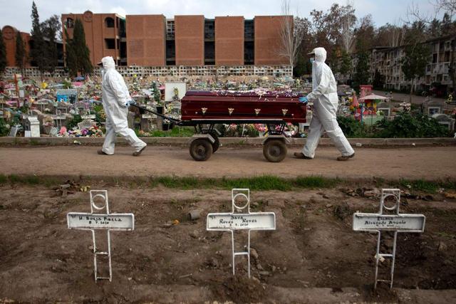El sepulturero Fernando Quezada (derecha), de 27 años, y un compañero de trabajo llevan un ataúd en medio de la pandemia de coronavirus en el Cementerio General de Santiago de Chile. (AFP / Claudio REYES).