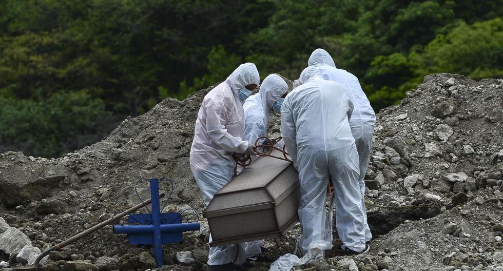 Hombres con trajes protectores entierran el ataúd de un pariente que murió de coronavirus COVID-19 en las afueras de Tegucigalpa, Honduras. (Foto: ORLANDO SIERRA / AFP).