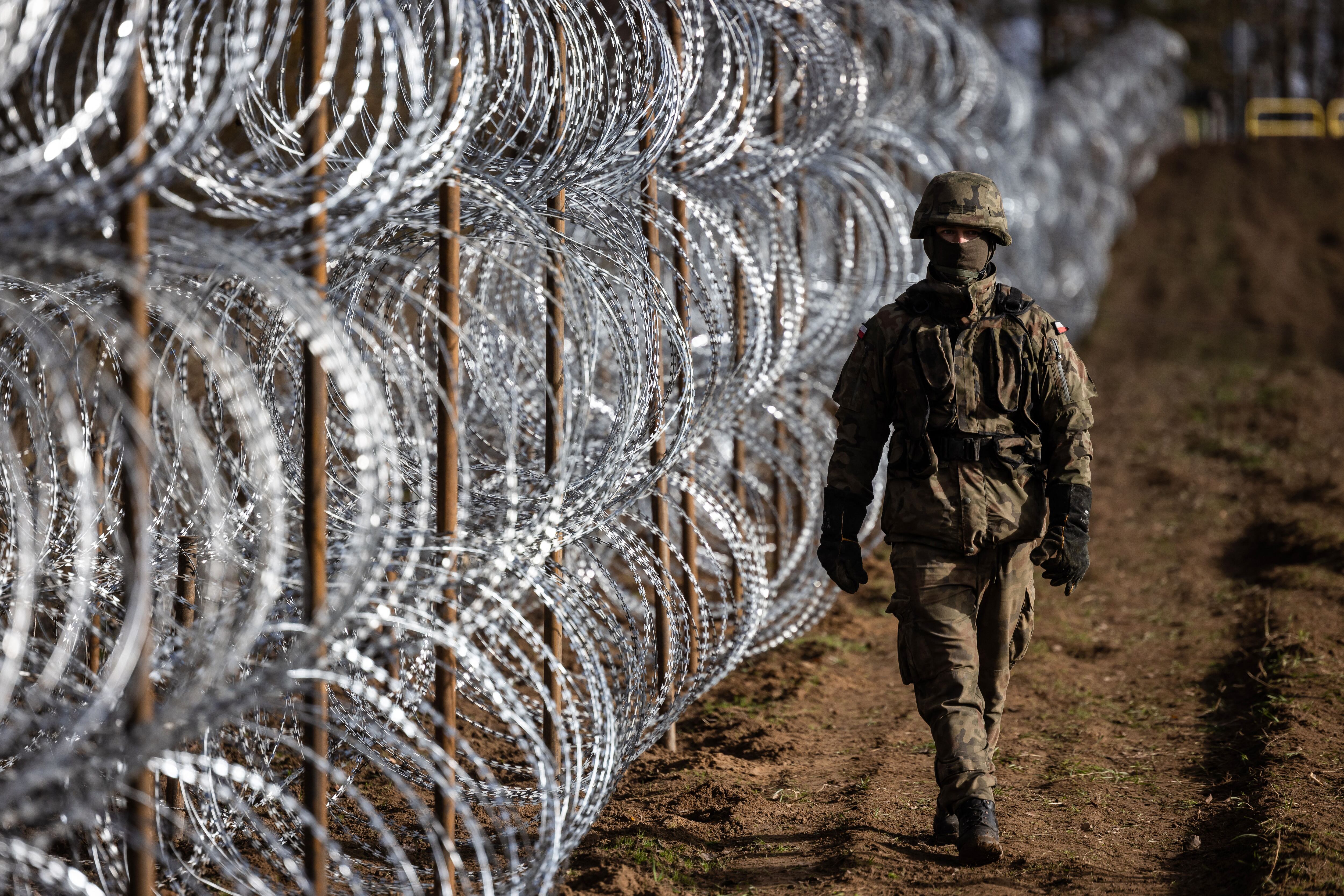 A Polish soldier is pictured during the construction of a concertina fence on the Polish-Russian border in the Kaliningrad Oblast, Zerdziny region, north-eastern Poland, on November 3, 2022. (Photo by Wojtek RADWANSKI / AFP)