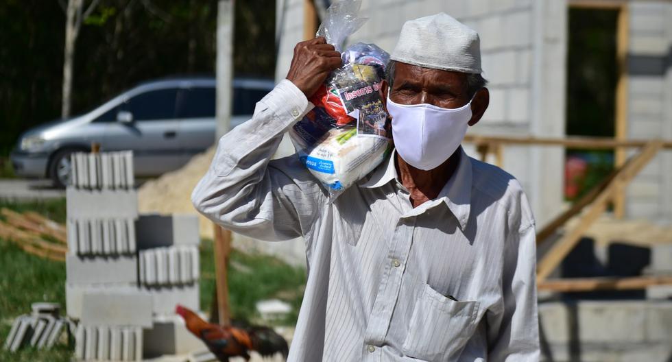 El nuevo coronavirus podría agudizar este año la situación de las poblaciones al borde de la hambruna. Un hombre es visto llevando donaciones de alimentos en Tailandia. (Madaree TOHLALA / AFP).