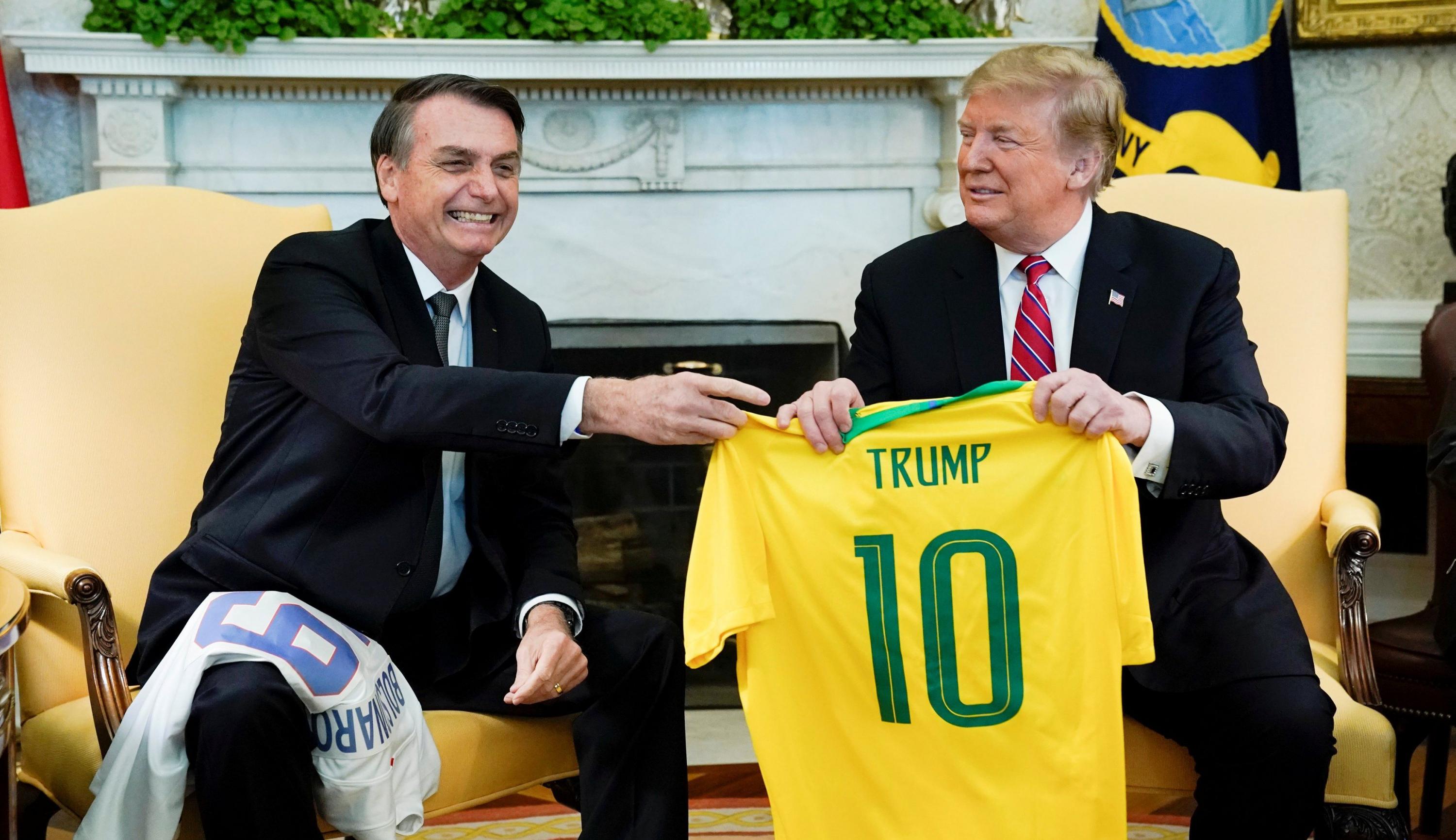 Jair Bolsonaro es recibido por Donald Trump en la Casa Blanca. El presidente de Brasil le regaló una camiseta de la selección de fútbol de su país. (Reuters).