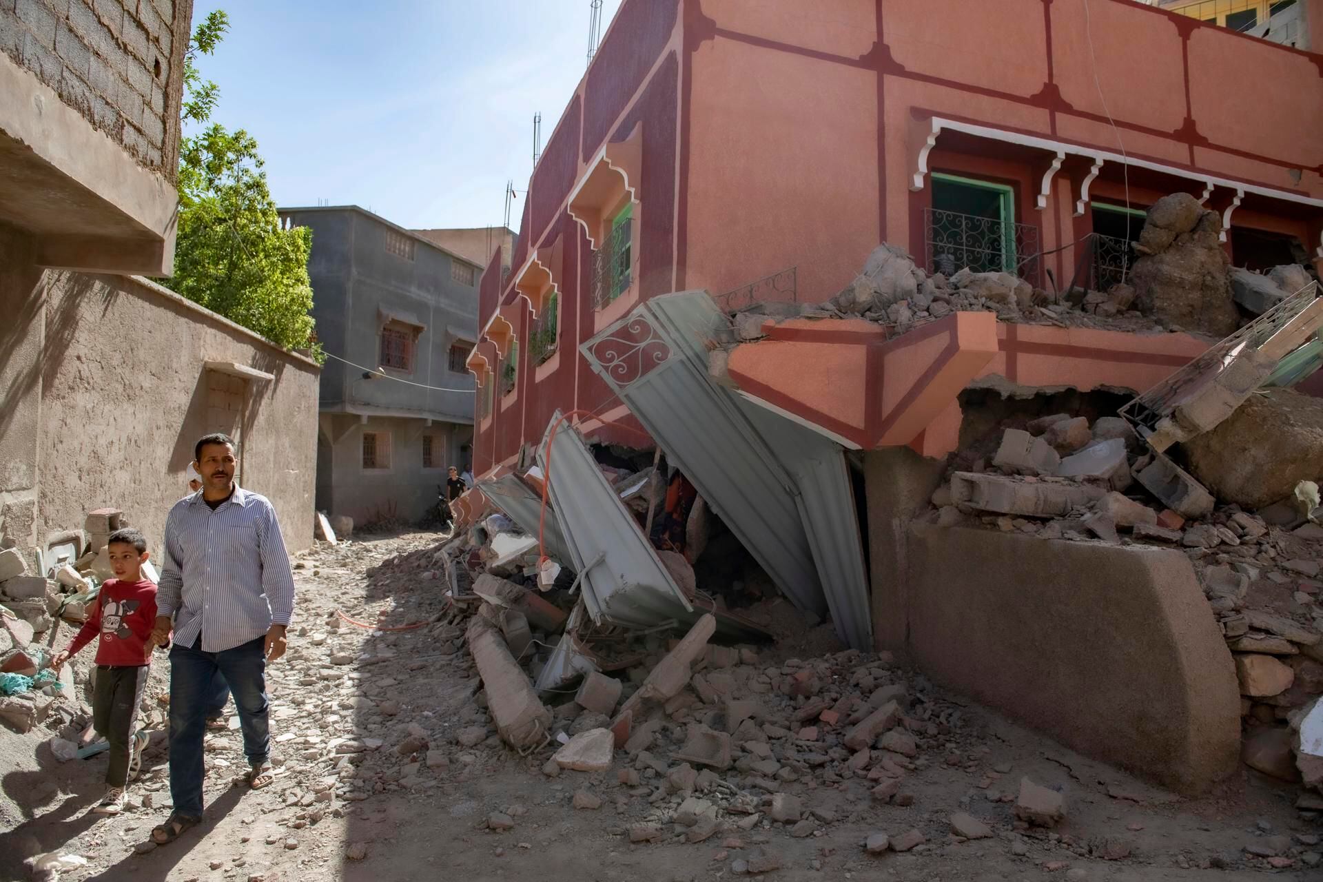 A person with a child walks next to a damaged building after an earthquake in Marrakech, Morocco, September 9, 2023. (Photo: EFE/EPA/JALAL MORCHIDI)