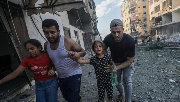 Dos hombres ayudan a dos niñas heridas a abandonar la zona tras un ataque aéreo de Israel en Gaza, el 21 de octubre de 2023. (EFE/EPA/MOHAMMED SABRE).