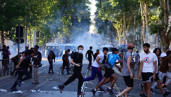 Manifestantes huyen de botes de gas lacrimógeno lanzados durante enfrentamientos con la policía en Marsella, sur de Francia. (Foto de CLEMENT MAHOUDEAU / AFP)