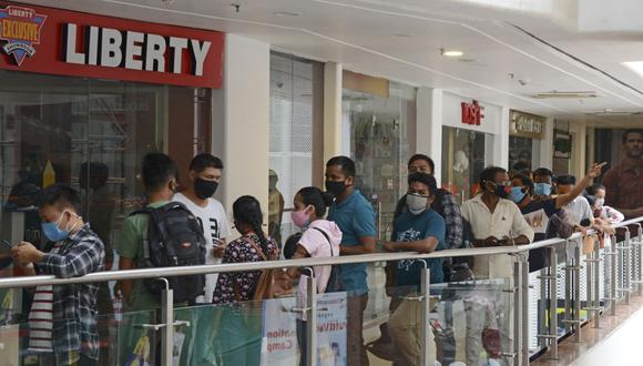 Empleados de un centro comercial y público en general hacen cola para vacunarse contra el coronavirus Covid-19 en la India (Foto de Diptendu DUTTA / AFP).