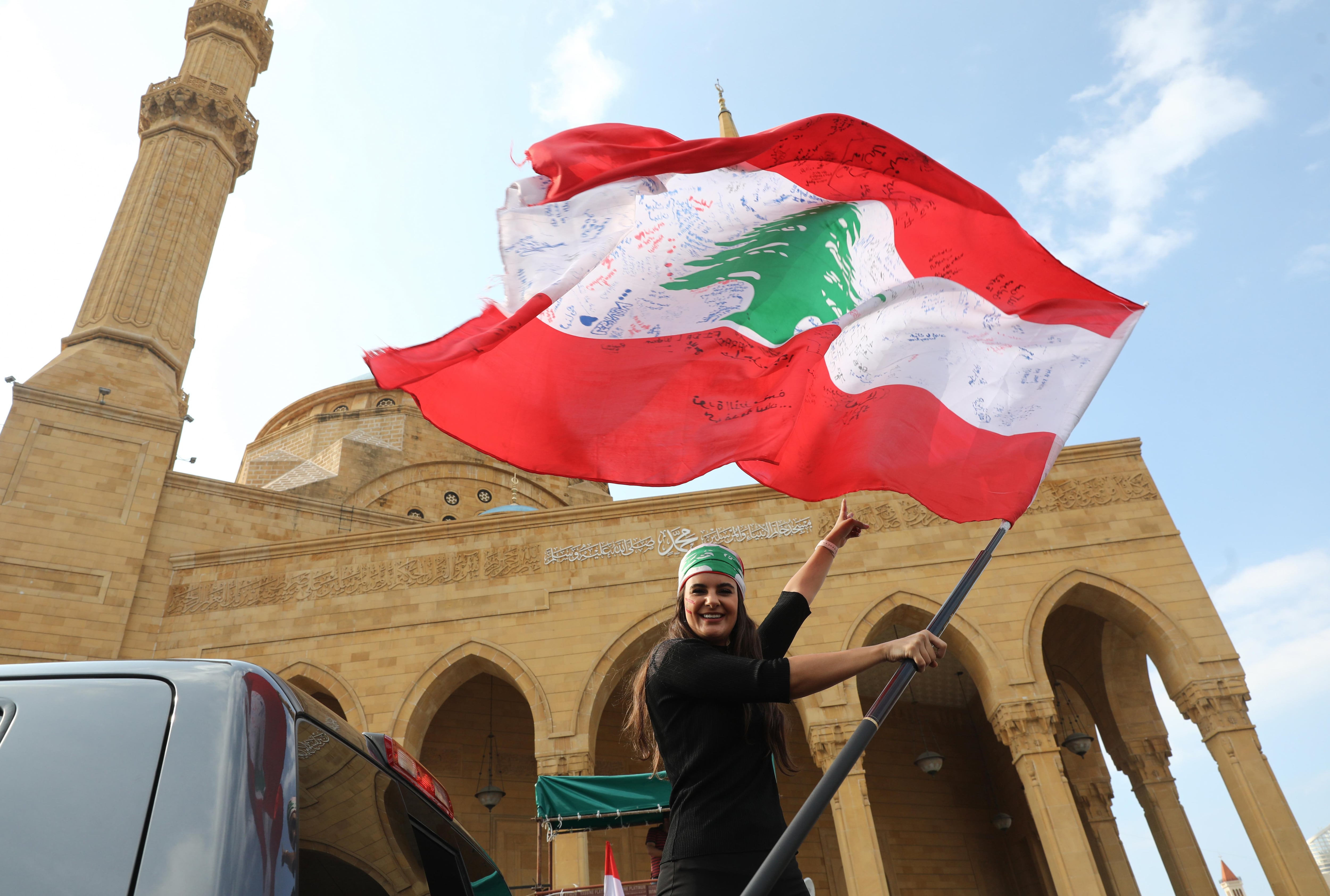 Una manifestante libanesa antigubernamental ondea la bandera nacional mientras se prepara para dirigirse al sur del Líbano en un autobús 'revolucionario' desde el centro de Beiru. (Foto: AFP)