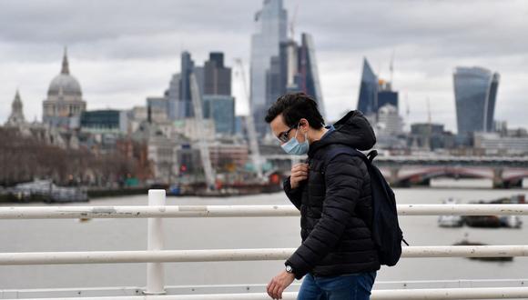 Un peatón que se protege del coronavirus con una mascarilla camina por el puente de Waterloo para cruzar el río Támesis, en Londres, Inglaterra, el 29 de enero de 2022. (JUSTIN TALLIS / AFP).