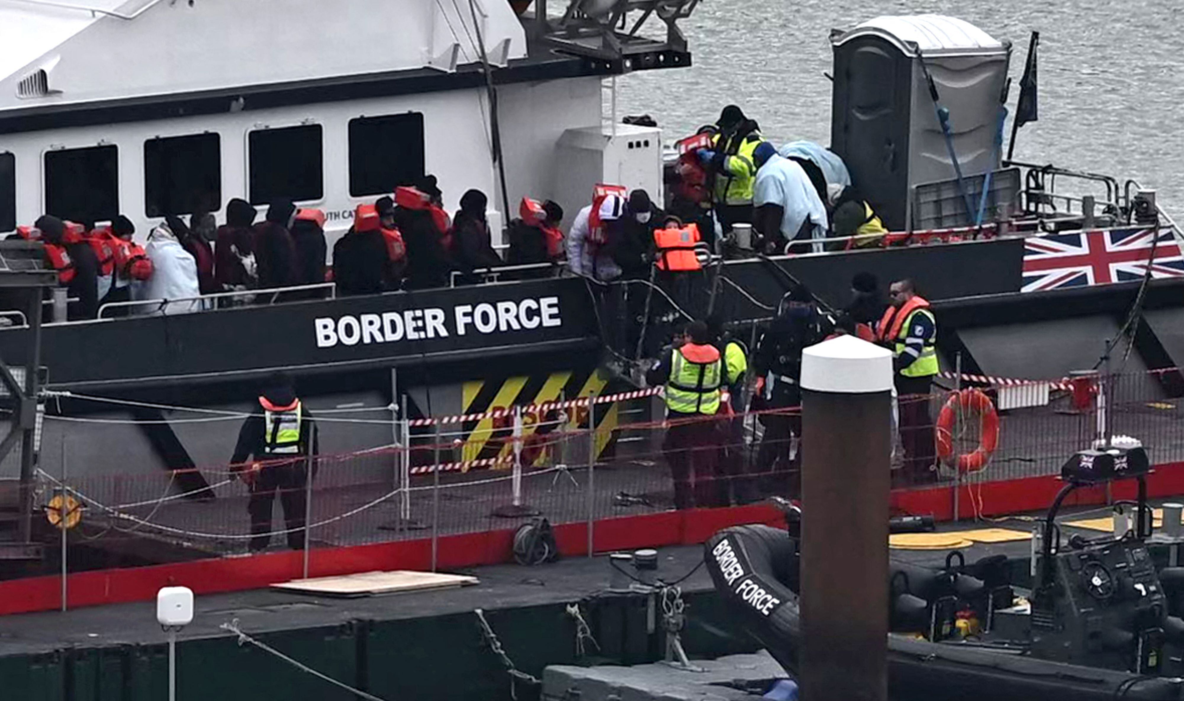 Migrants are escorted ashore from the UK Border Force ship 