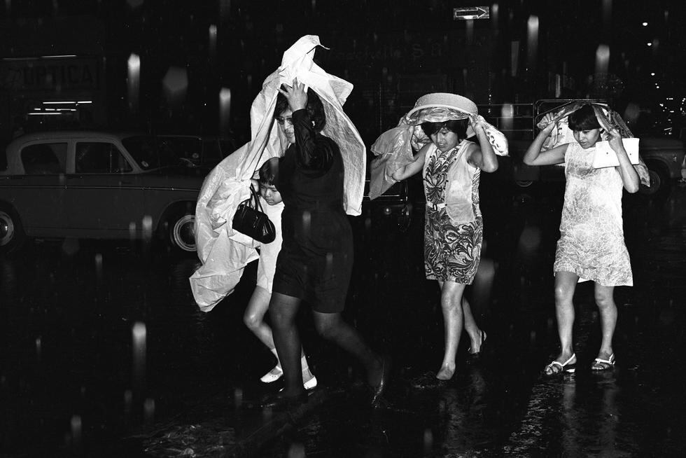 15 de enero de 1970, lluvias torrenciales afectan a la ciudad de Lima. En la imagen un grupo de mujeres se protegen con plásticos y bateas de la fuerte lluvia. (Foto GEC Archivo Histórico) 
