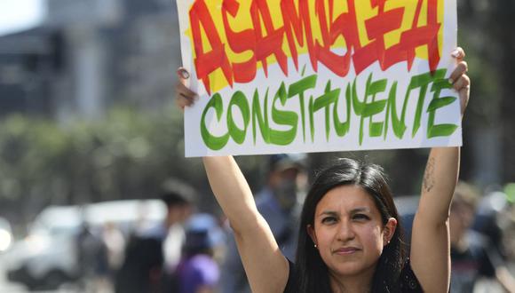 Una mujer sostiene un letrero que dice "Asamblea Constituyente" mientras la gente se manifiesta en Santiago de Chile el 24 de octubre de 2019. (Foto de Martin BERNETTI / AFP).