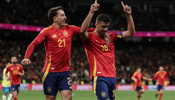 Spain's midfielder #16 Rodri celebrates scoring his team's third goal with Spain's forward #21 Mikel Oyarzabal during the international friendly football match between Spain and Brazil at the Santiago Bernabeu stadium in Madrid on March 26, 2024. Spain arranged a friendly against Brazil at the Santiago Bernabeu under the slogan "One Skin" to help combat racism. (Photo by Thomas COEX / AFP)