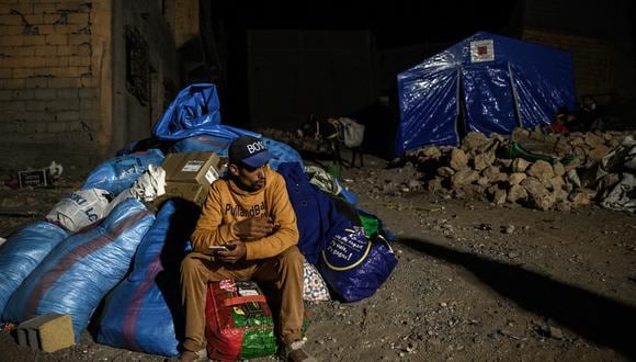 Imagen de archivo | Un superviviente del terremoto se sienta sobre una pila de suministros donados en la aldea de Moulay Brahim, en la provincia central de Al-Haouz. (Foto de Philippe LÓPEZ / AFP)