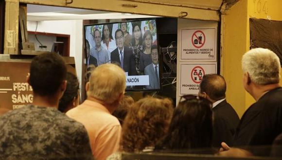 Un grupo de ciudadanos reunidos en el Centro de Lima observa el mensaje a la nación en el que el presidente Martín Vizcarra anunciaba el inicio del estado de emergencia, en la noche del 15 de marzo. (Foto: César Zamalloa/GEC).
