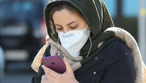El carácter desconocido del coronavirus COVID-19 sirve de terreno fértil para alimentar las ‘fake news’. En esta foto de inicios de marzo, una mujer revisa su celular en Teherán. (Photo by ATTA KENARE / AFP)