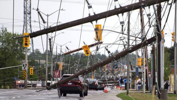 Se ve un vehículo entre líneas eléctricas caídas y postes de servicios públicos después de una gran tormenta en Merivale Road en Ottawa, Canadá.