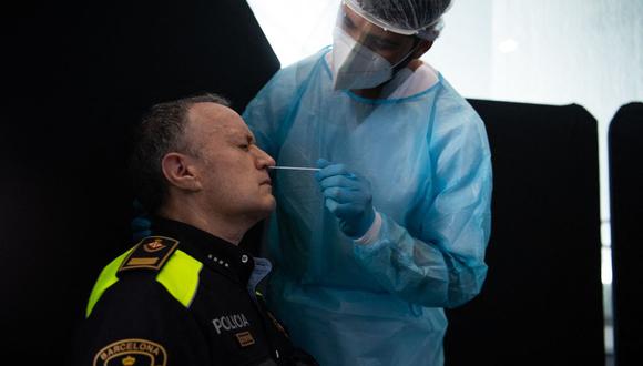 Personal sanitario toma una muestra de un hisopo de un policía para realizar la prueba del coronavirus Covid-19 en Barcelona, España, el 20 de mayo de 2021. (Foto de Josep LAGO / AFP).