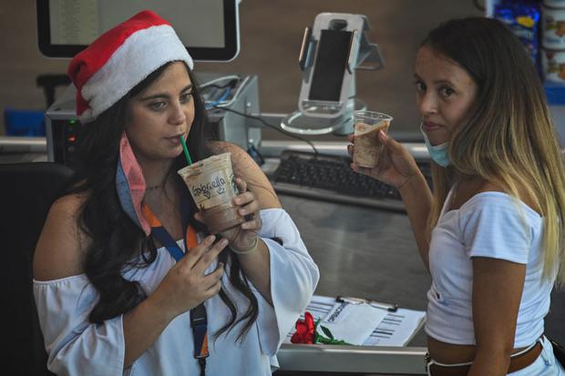 Dos mujeres beben café en un supermercado del distrito de Las Mercedes en Caracas, el 23 de diciembre de 2021. (Federico PARRA / AFP).