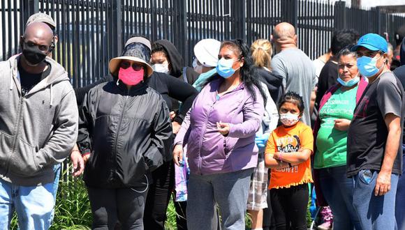 Las personas usan sus máscaras faciales mientras esperan en una línea de distribución de alimentos de emergencia frente a la Iglesia de Dios del Templo de la Calle 88 en Cristo en California. (Foto: Frederic J. BROWN / AFP).