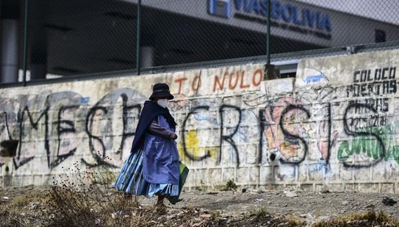 Una mujer pasa junto a un graffiti contra el candidato presidencial Carlos Mesa, en El Alto, Bolivia, el 17 de octubre de 2020. (Foto de Ronaldo SCHEMIDT / AFP).