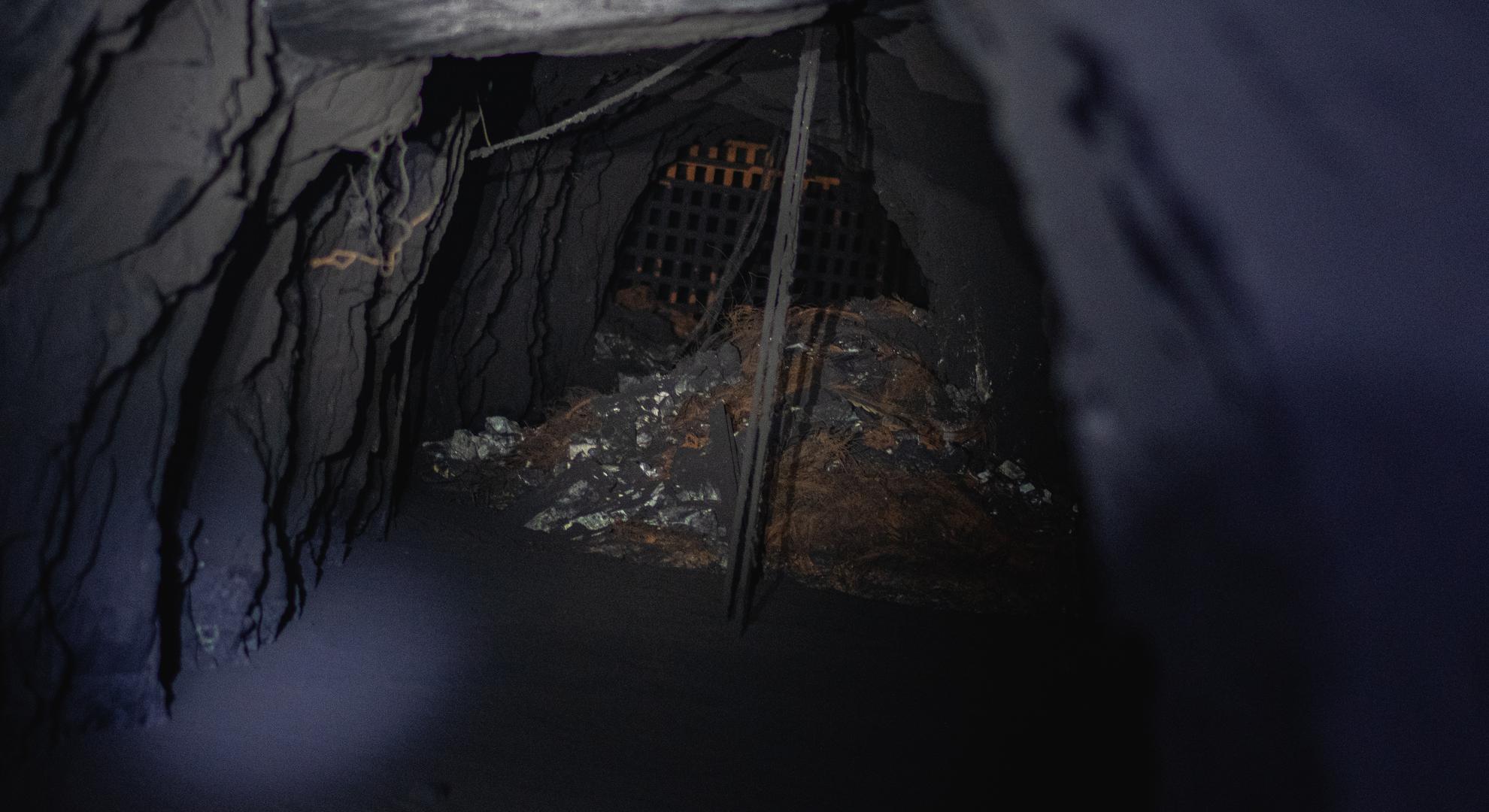 La reja al fondo fue instalada por Poderosa para evitar que los mineros ilegales o parqueros accedan a las operaciones de la minera. Las rocas están negras por el humo, al igual que el agua en el suelo, cubierta de restos espesos.