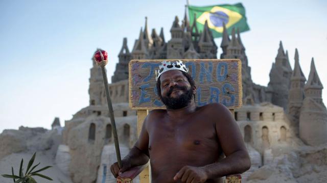 Brasil. Con su corona de rey en la cabeza, Marcio Mizael Matolias repara con esmero su castillo, a pesar de los 40 grados que asfixian a los bañistas en la playa de Río de Janeiro en esta tarde de enero. (Foto: AFP)
