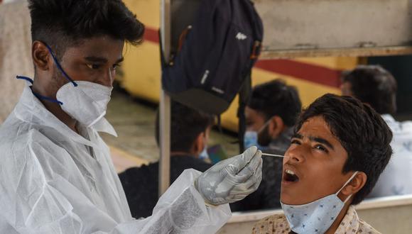 Un trabajador de la salud toma una muestra de hisopado nasal de un pasajero para la prueba del coronavirus después de llegar a una plataforma ferroviaria en un tren de larga distancia en Mumbai (India), el 9 de julio de 2021. (Foto de Punit PARANJPE / AFP).