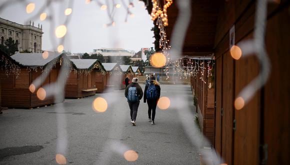 Dos jóvenes pasean por un mercadillo navideño de Viena cerrado en el primer día del confinamiento decretado por el Gobierno de Austria, el pasado 22 de noviembre, ante el aumento de los contagios de coronavirus. (EFE/EPA/CHRISTIAN BRUNA).