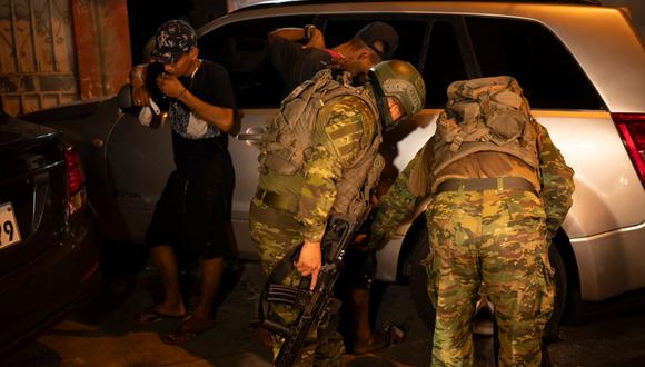 Soldados de la Quinta Brigada de Infantería cachean a dos hombres mientras participaban con policías en un operativo de seguridad y búsqueda de sospechosos durante el toque de queda, en un barrio pobre de Guayaquil, Ecuador, en la madrugada del 12 de enero de 2024 | Foto: YURI CORTEZ / AFP