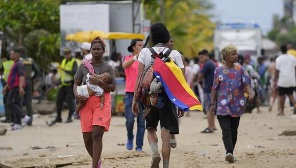 Un migrante lleva una bandera venezolana en Necoclí, Colombia, un punto de parada para los migrantes que toman botes a Acandi que conduce al Tapón del Darién.