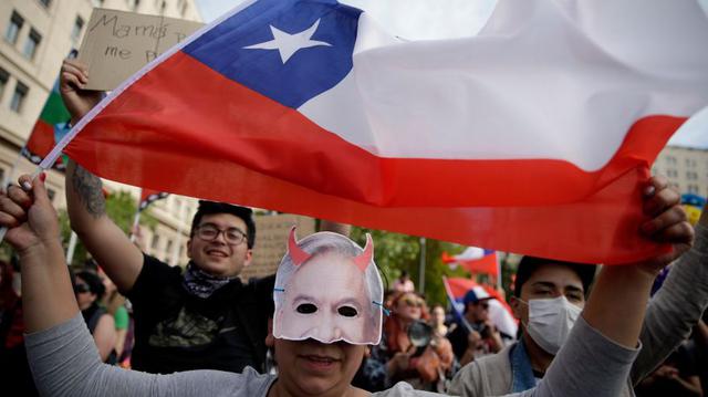 Una manifestante sostiene una bandera de Chile este sábado durante una protesta contra el Gobierno del presidente Sebastián Piñera frente al Palacio de La Moneda, en Santiago. (Foto: EFE)