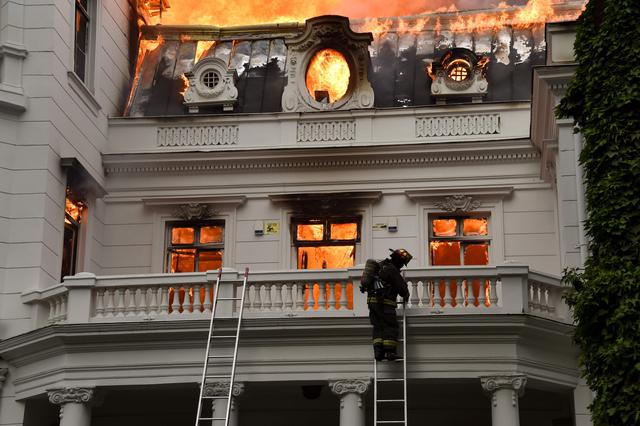 Un edificio patrio en el centro de Santiago de Chile se incendió este viernes cerca de la Plaza Italia, donde cientos de miles de personas se manifestaban en el día que se cumplen tres semanas de protestas en el país, que han dejado 20 fallecidos, seis de ellos ciudadanos extranjeros. (Foto: AFP).