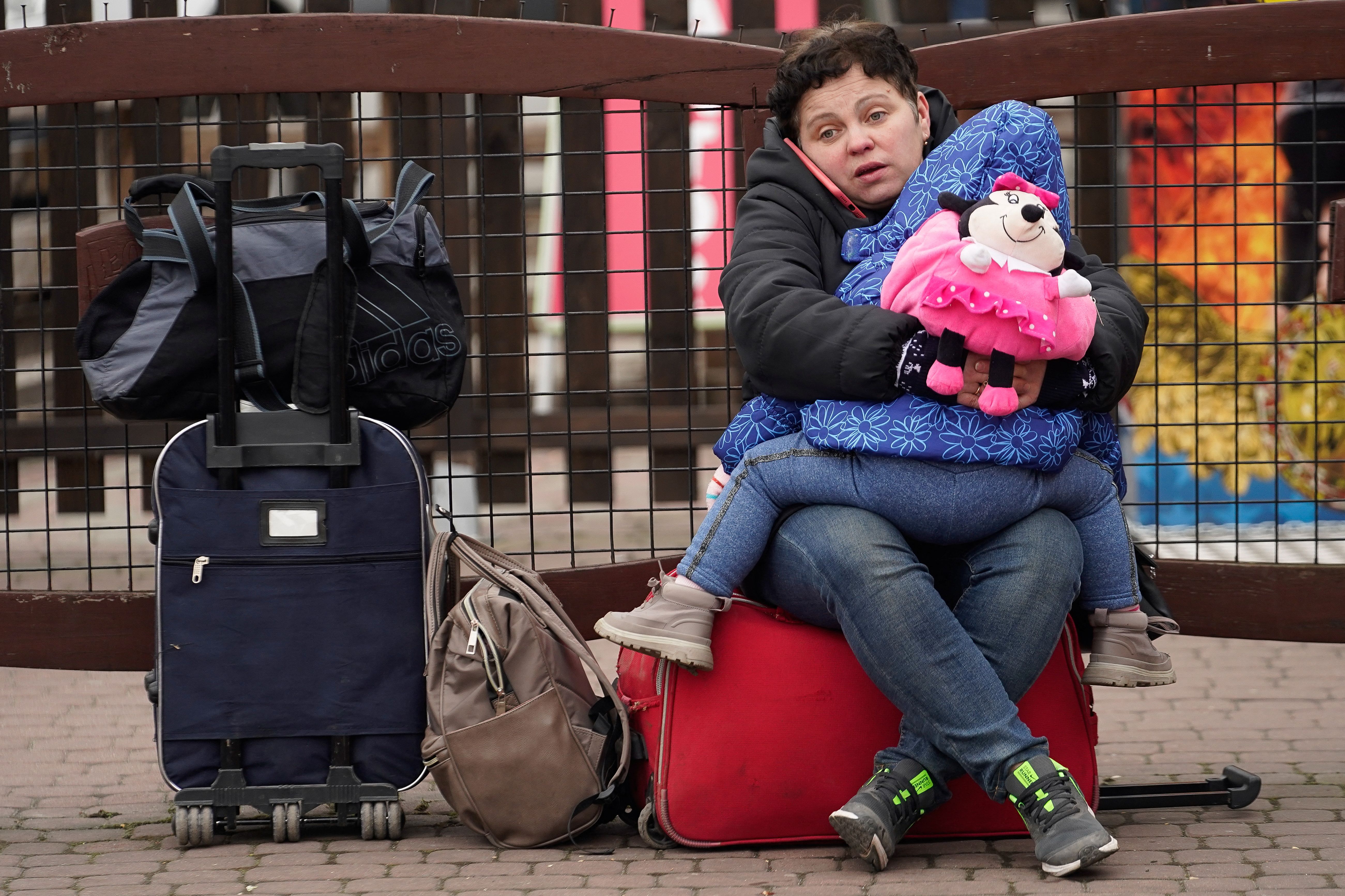 A woman sits with her daughter after crossing the border to flee violence in Ukraine, at the Medyka border crossing, Poland.  (REUTERS/Bryan Woolston).