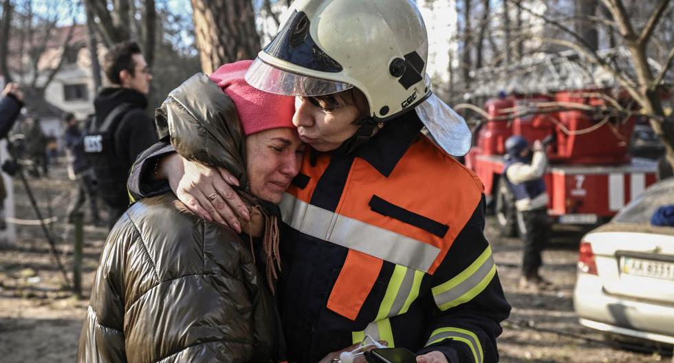Una residente evacuada es consolada por personal de rescate frente a un edificio de apartamentos en llamas en Kiev, Ucrania, el 15 de marzo de 2022, después de que los ataques rusos contra zonas residenciales. (ARIS MESSINIS / AFP).