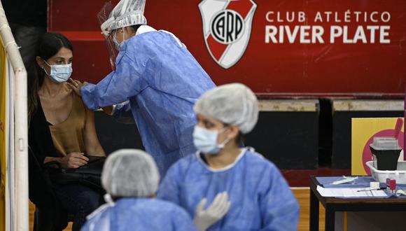 Un trabajador de la salud recibe una dosis de la vacuna Sputnik V contra el coronavirus, en la cancha de baloncesto del club argentino River Plate, debajo de la tribuna del estadio Monumental, en Buenos Aires (Argentina), el 2 de febrero de 2021. (Juan MABROMATA / AFP).