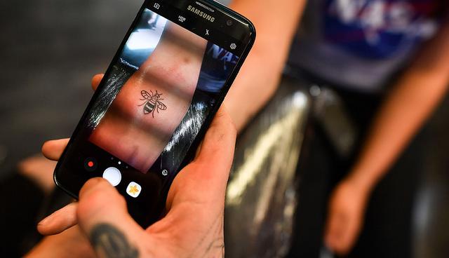 A tattoo artist inks a bee logo, synonymous with Manchester as a symbol of the city's industrial heritage, and rapidly becoming a symbol of resilience following the May 22 Manchester Arena bombing attack, at Tattitude, a tattoo parlour in Manchester, northwest England on May 26, 2017. Since the May 22 attack at an Ariana Grande concert, tattoo parlours across the Manchester have been overrun with requests for tattoos of bees -- a symbol of the city and its residents' proud spirit.  / AFP / Ben STANSALL