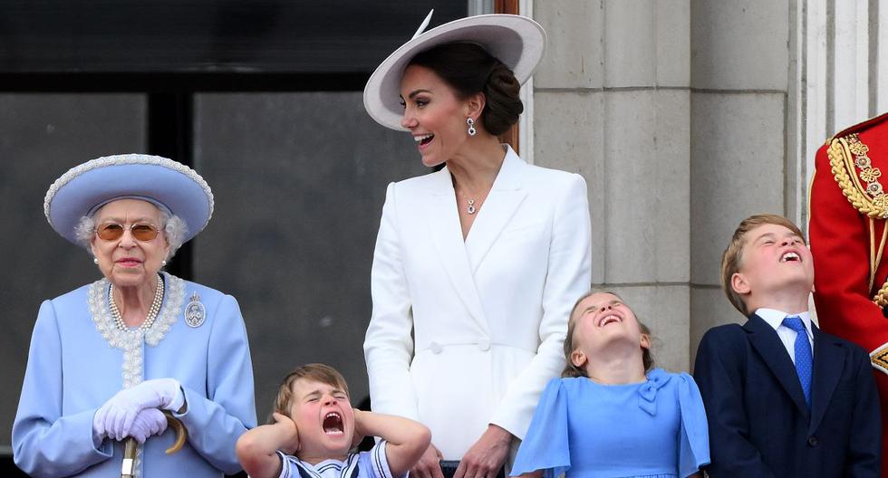 El príncipe Luis de Cambridge se sujeta las orejas mientras está de pie junto a la reina Isabel II, su madre Catalina, la princesa Charlotte y el príncipe Jorge. (DANIEL LEAL / AFP).