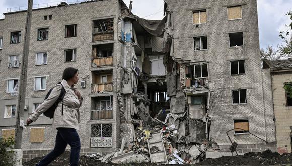 Una mujer camina junto a un edificio de apartamentos destruido en Bakhmut, en la región oriental del Donbás, en Ucrania, el 22 de mayo de 2022. (ARIS MESINIS / AFP).