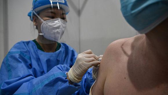 Imagen referencial. Una trabajadora médica (izquierda) inocula a un periodista con la vacuna Sinopharm contra el coronavirus en Beijing  (China), el 15 de abril de 2021. (Noel Celis / AFP).