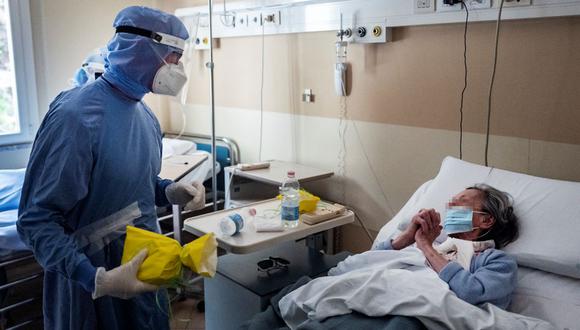 Una paciente infectada de coronavirus reacciona antes de recibir un pastel de pascua tradicional entregado por el doctor Paolo Russo el 4 de abril de 2021 en Turín, Italia. (MARCO BERTORELLO / AFP).