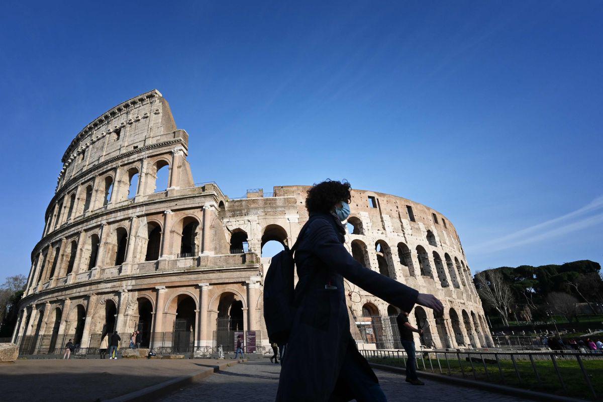 Un turista que usa una máscara respiratoria como parte de las medidas de precaución contra la propagación del nuevo coronavirus COVID-19, pasa junto al monumento cerrado del Coliseo en Roma. (AFP).