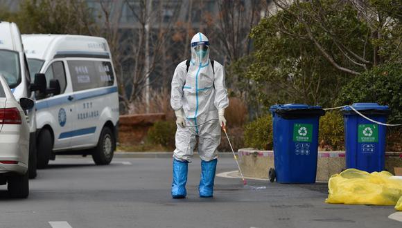 Un trabajador rocía desinfectante afuera de un hotel después de que una persona diera positivo a coronavirus en Nanjing, en la provincia de Jiangsu, en el este de China, el 28 de diciembre de 2021. (STR / AFP).